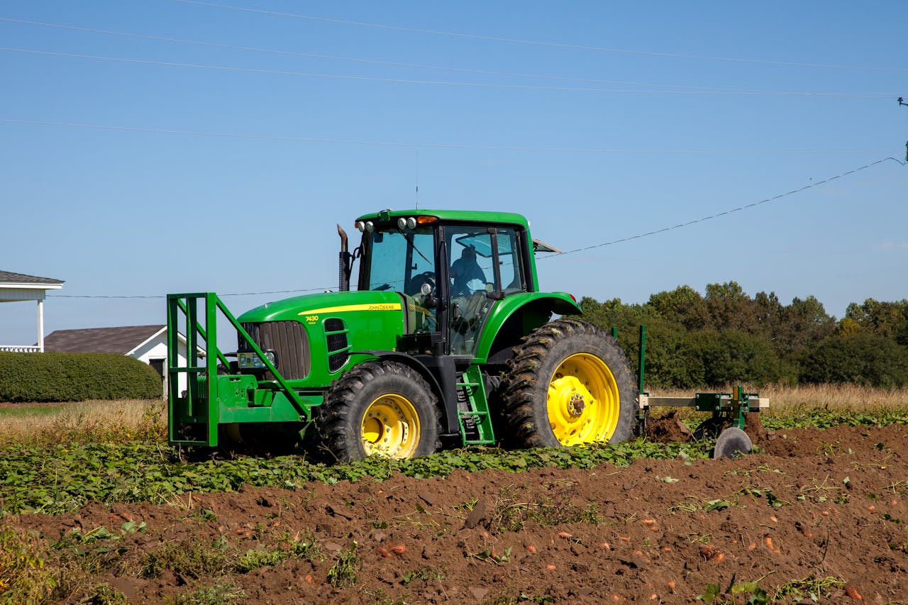 A powerful green tractor cultivating a field in rural North Carolina.